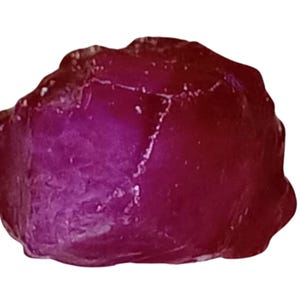 May include: A large, rough, red ruby gemstone. The ruby has a deep, rich red colour and is translucent.