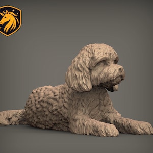 Puede incluir: Una figura monocromática de color marrón claro de un perro de pelo rizado en posición tumbada. La escultura presenta un pelaje texturizado y detallado en todo el cuerpo, las orejas y la cola, con un acabado liso y sólido en toda la figura.