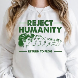 May include: White sweatshirt with green text that reads "REJECT HUMANITY - RETURN TO FROG" and a graphic of a frog and human evolution.