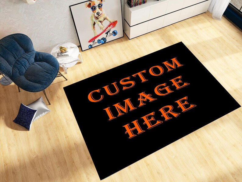 May include: A black rectangular rug with the words "CUSTOM IMAGE HERE" in orange. The rug is on a wooden floor, with a blue chair and a framed picture of a dog in sunglasses in the background.