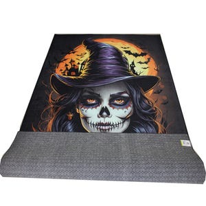 May include: A Halloween-themed rug with a colorful illustration of a witch with a skull face and a purple hat. The witch is in front of a large orange moon with bats flying around it.