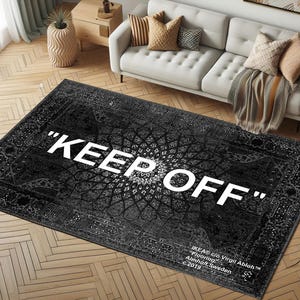 May include: Black and white rug with a traditional Persian design and the text "KEEP OFF" in white. The rug has a white border and the text "IKEA ©/o Virgil Abloh™ Flooring Älmhult, Sweden c. 2019" in the bottom right corner.