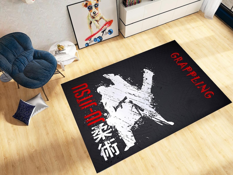 May include: Black rectangular rug featuring a white graphic of two figures in a grappling position. The words "JIU-JITSU" and "GRAPPLING" are in red, with Japanese characters below. The rug is on a wooden floor.