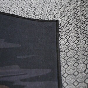 May include: Close-up of a black fabric with a subtle pattern of gray clouds. The fabric has a black stitched border.