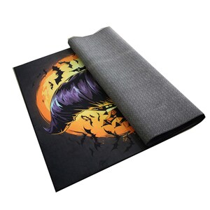 May include: A black and orange Halloween-themed doormat with a purple witch flying over a full moon. The witch is holding a broom and has a black cat on her shoulder. There are bats flying around the moon.