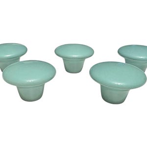 May include: Five light blue ceramic cabinet knobs with a rounded top and a short stem.