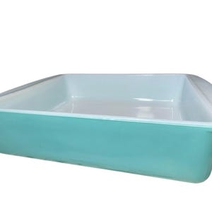 May include: A turquoise blue baking dish with a white interior. The dish is made of glass and has a rectangular shape.