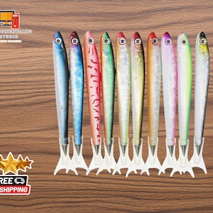 May include: A set of ten colorful fish-shaped pens with white plastic tails. The pens are arranged in a row on a wooden surface.