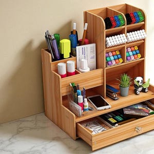May include: A wooden desk organizer with multiple compartments and a drawer. It features sections for pens, markers, and other office supplies. The organizer also has a small drawer and a shelf with a small plant and a panda figurine.