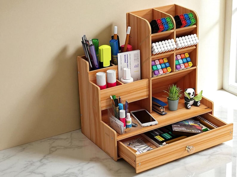 May include: A wooden desk organizer with multiple compartments and a drawer. It features sections for pens, markers, and other office supplies. The organizer also has a small drawer and a shelf with a small plant and a panda figurine.