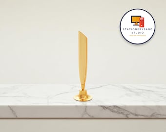 May include: A gold-colored pen holder with a flared base and a sleek, angled top. The pen holder is displayed on a white marble surface, with the "STATIONERYSANC STUDIO DESKTOP ORGANIZER" logo in the background.