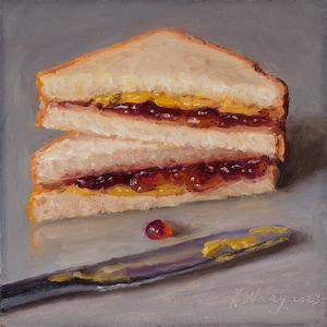 Könnte beinhalten: Eine Nahaufnahme eines Erdnussbutter- und Marmeladensandwiches auf einer grauen Oberfläche. Das Sandwich ist in zwei Hälften geschnitten und neben dem Sandwich liegt ein Messer mit Erdnussbutter.