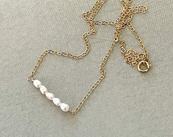 May include: A delicate gold chain necklace with a row of small white pearls.