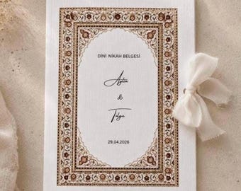 May include: A white wedding invitation with a decorative brown border and text. The invitation is tied with a white ribbon. The text includes names and the date 29.04.2026.
