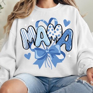 May include: A white ceramic mug with a black handle and the text "But First, Coffee" in a black, bold font. The mug is sitting on a wooden surface. The mug is approximately 4 inches tall.