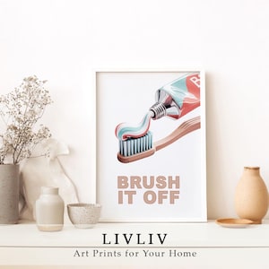Puede incluir: Una impresión artística enmarcada que presenta un cepillo de dientes con pasta dental que se exprime sobre las cerdas. La impresión tiene las palabras "BRUSH IT OFF" en una fuente marrón claro. La parte inferior de la impresión tiene el texto "LIVLIV Art Prints for Your Home".