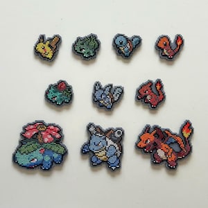 May include: A set of ten cross-stitched Pokémon character patches in various colours. The patches depict different Pokémon in bright colours, including yellow, green, blue, and red, with grey borders. Ideal for crafting and customisation projects.