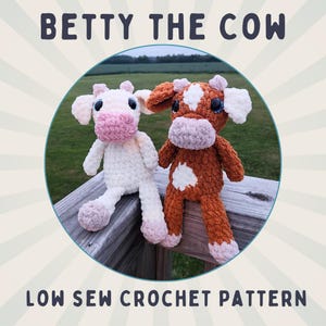 May include: Two crocheted cow plushies, one white and one brown with white spots, sitting on a wooden railing. The plushies have pink noses and blue eyes. The text "BETTY THE COW LOW SEW CROCHET PATTERN" is at the top of the image.