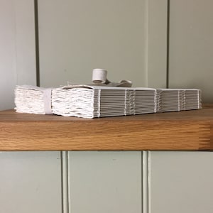 Cotton Rag Sketchbook with handmade khadi paper and natural linen ribbon. An exposed spine style, chunky size angled towards the camera.