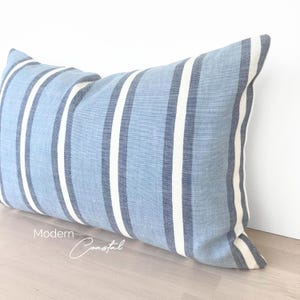 May include: A blue and white striped throw pillow with a modern coastal design.