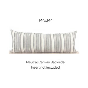 May include: A gray and white striped lumbar pillow with a neutral canvas backside. The pillow measures 14 inches by 34 inches. Insert not included.