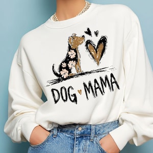 May include: White crew neck sweatshirt featuring a graphic of a dog with a floral pattern, a brown heart, and the words "DOG MAMA". The dog is brown and black, with pink and white flowers. The sweatshirt is a casual style.