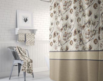 May include: A beige shower curtain with a pattern of white cotton blossoms and brown branches. The bottom of the curtain has a beige and brown stripe.