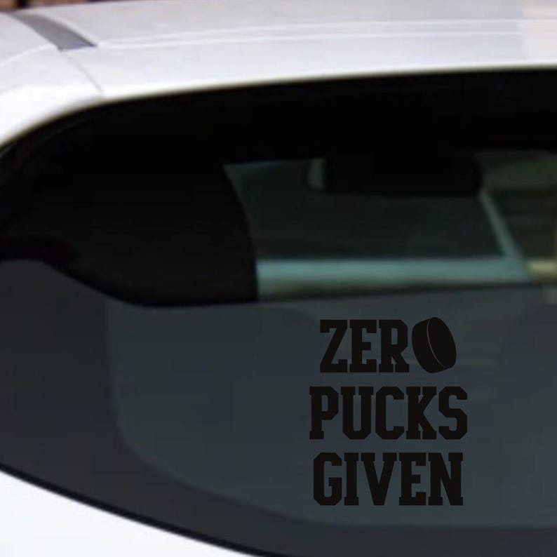 May include: Black vinyl decal with the words "ZERO PUCKS GIVEN" and a hockey puck graphic. The decal is applied to the rear window of a vehicle.