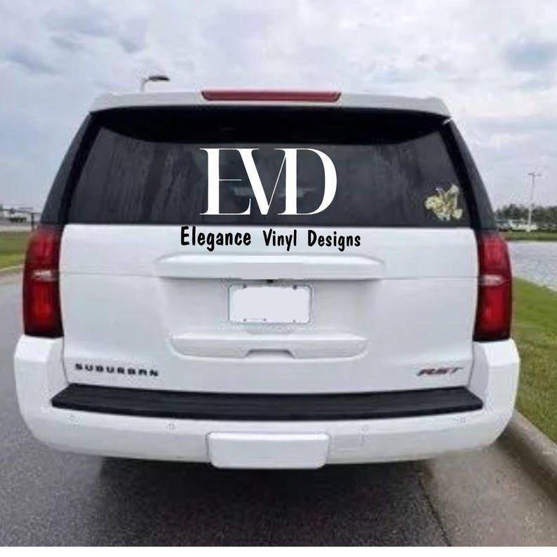 May include: White SUV with a custom vinyl decal on the back window. The decal says "EVD Elegance Vinyl Designs".