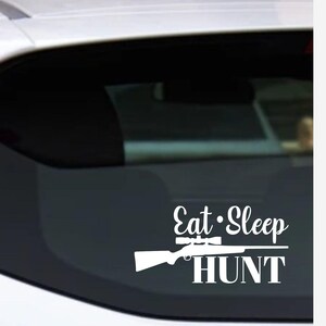 May include: White vinyl decal with the words "Eat Sleep HUNT" and a rifle with a scope. The decal is designed to be applied to a car window or other smooth surface.