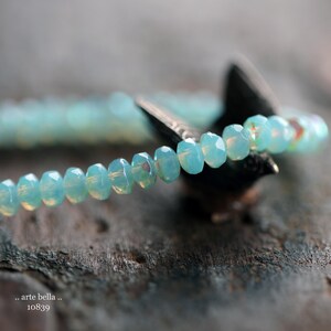 May include: A delicate bracelet made of light blue faceted beads. The bracelet is strung on a clear elastic cord and is approximately 7 inches in length.