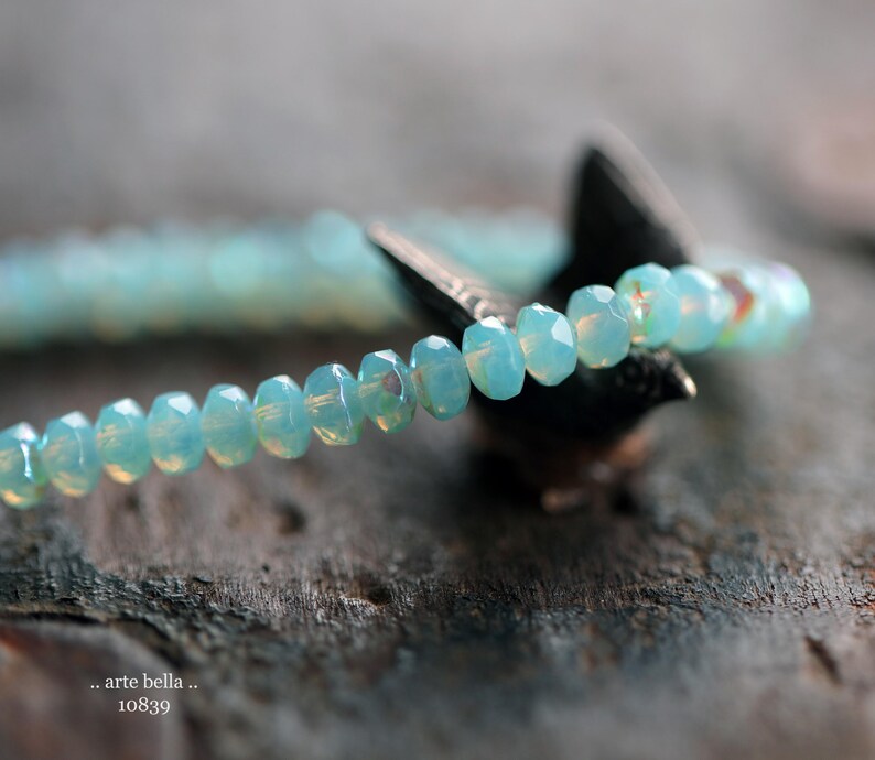 May include: A delicate bracelet made of light blue faceted beads. The bracelet is strung on a clear elastic cord and is approximately 7 inches in length.