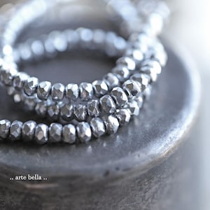 May include: A silver necklace made of faceted beads. The beads are arranged in a layered, cascading design.