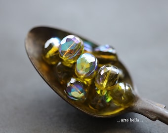 May include: A spoon filled with iridescent yellow and green glass beads. The beads have a faceted, diamond-like shape.