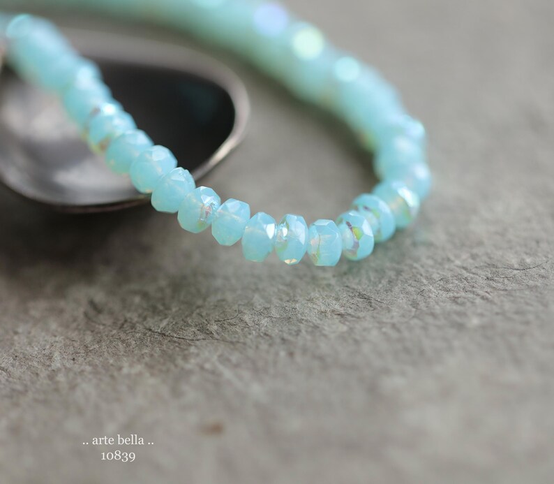 May include: A delicate bracelet made of light blue faceted beads. The beads are strung together to form a simple, elegant design.
