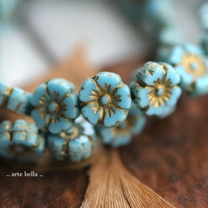 Könnte beinhalten: Nahaufnahme einer türkisblauen und goldenen Blumenperlenkette. Die Perlen sind aus Glas und haben einen Vintage-Look.