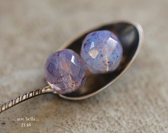 May include: Two faceted, translucent light purple beads with internal reddish-brown inclusions resting in a metallic spoon. The text ".. arte bella .. 2148" is printed in the lower left corner of the image, indicating the product identification.