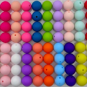Könnte beinhalten: Sortiment von 60 bunten Silikonperlen, perfekt zum Basteln von Schmuck oder zum Erstellen von sensorischen Spielzeugen. Die Perlen sind rund und in verschiedenen Farben erhältlich, darunter Rosa, Blau, Grün, Gelb und Orange.