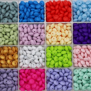 May include: A storage box filled with 12 different colors of silicone beads. The beads are all the same shape and size, and they are arranged in rows. The beads are perfect for making jewelry, crafts, or toys.