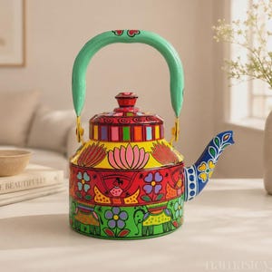 May include: A metal tea kettle featuring a vibrant hand-painted design with a mint green handle. The body displays colourful patterns including pink lotus flowers, red and green bands, floral motifs, and stylized elephants on a yellow and green base.