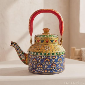May include: A metal teapot featuring a vibrant hand-painted design with a red handle, a yellow upper section, and a blue base adorned with floral patterns. The surface is embellished with numerous small, clear, reflective crystals throughout.