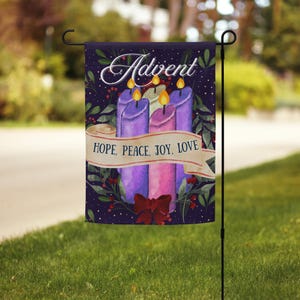 May include: A garden flag with a watercolor design. The flag features four lit candles in shades of purple and pink, with the word "Advent" at the top. A banner reads "HOPE, PEACE, JOY, LOVE". A red bow is at the bottom.