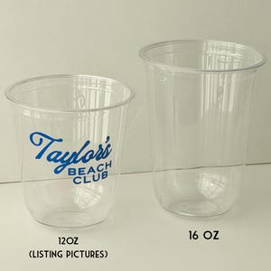 May include: Two clear plastic cups. One cup has the text "Taylor's BEACH CLUB" in blue. The smaller cup is labeled "12 OZ" and the larger cup is labeled "16 OZ". The smaller cup also has the text "(LISTING PICTURES)".