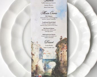 May include: A watercolor illustration of a canal in Venice, Italy, with buildings on either side. The illustration is on a white card with a menu for a wedding reception. The menu includes starters, main course, and dessert options. The starters include truffle mushroom arancini, caprese skewers, and petite crab cakes. The main course options are filet mignon, traditional Greek salad, pan-seared salmon, and wild mushroom risotto. The dessert options are creme brulee and apple crumble cake.