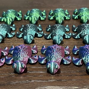 May include: A collection of 20 small, iridescent, 3D printed turtle figurines. The turtles are in shades of green, blue, and purple.