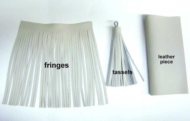 May include: A close-up of white leather tassels and fringes. The tassels are tied together with a loop of leather. The fringes are long and straight. The text "fringes" and "tassels" are written below the items. A rectangular piece of leather is in the background with the text "leather piece" written below it.