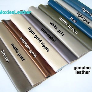 May include: A selection of ten leather swatches in various colors, including bronze, matte gold, antique gold, light gold ripple, gunmetal, white gold, army green, teal, light grey, and light teal. The swatches are arranged in a fan shape, with the bronze swatch at the bottom and the light teal swatch at the top. The text "genuine leather" is printed below the swatches.