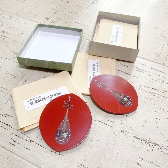 Genuine 1950s MCM coasters inlaid with Asian pipa instrument art, individually wrapped — actual vintage collectibles, not reproductions.