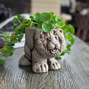 Puede incluir: Una taza de cerámica blanca con asa negra y el texto "But First, Coffee" en negro y negrita. La taza está sobre una superficie blanca.