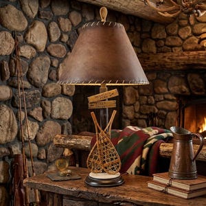 Lámpara de mesa vintage de los 90 con diseño rústico de cabaña de montaña junto al río, letreros de flechas y raquetas de nieve, con pantalla.